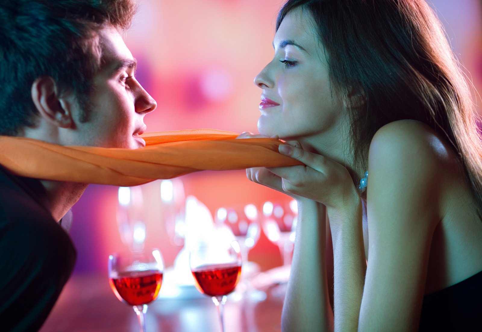 Young attractive happy couple kissing in restaurant, celebrating or on romantic date